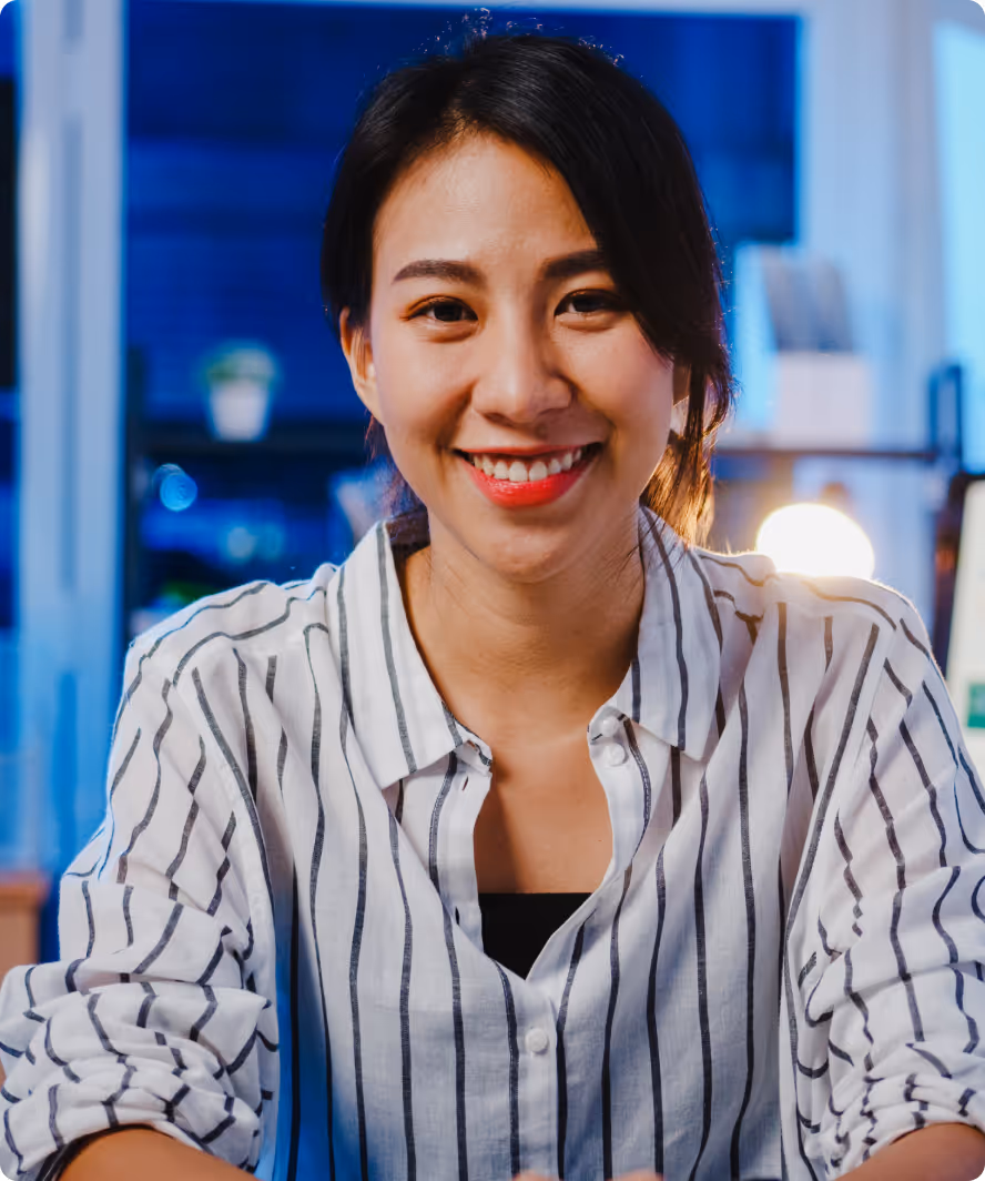 A woman smiles confidently at her desk, showcasing the support of NetSuite managed services in her workspace.