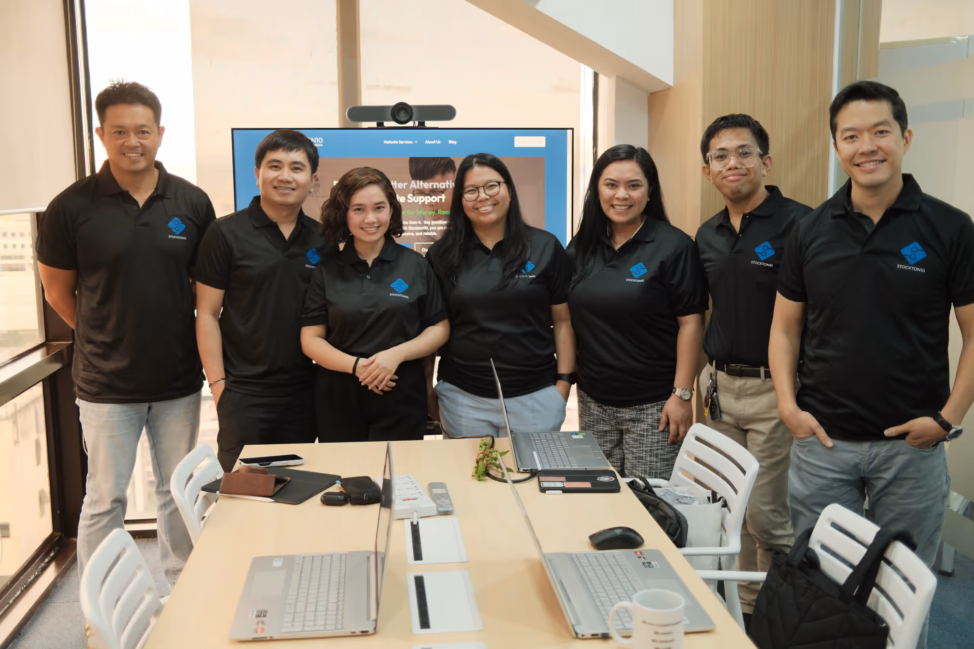 A group of people in black shirts collaborates around a table, embodying teamwork and dedication to client satisfaction.