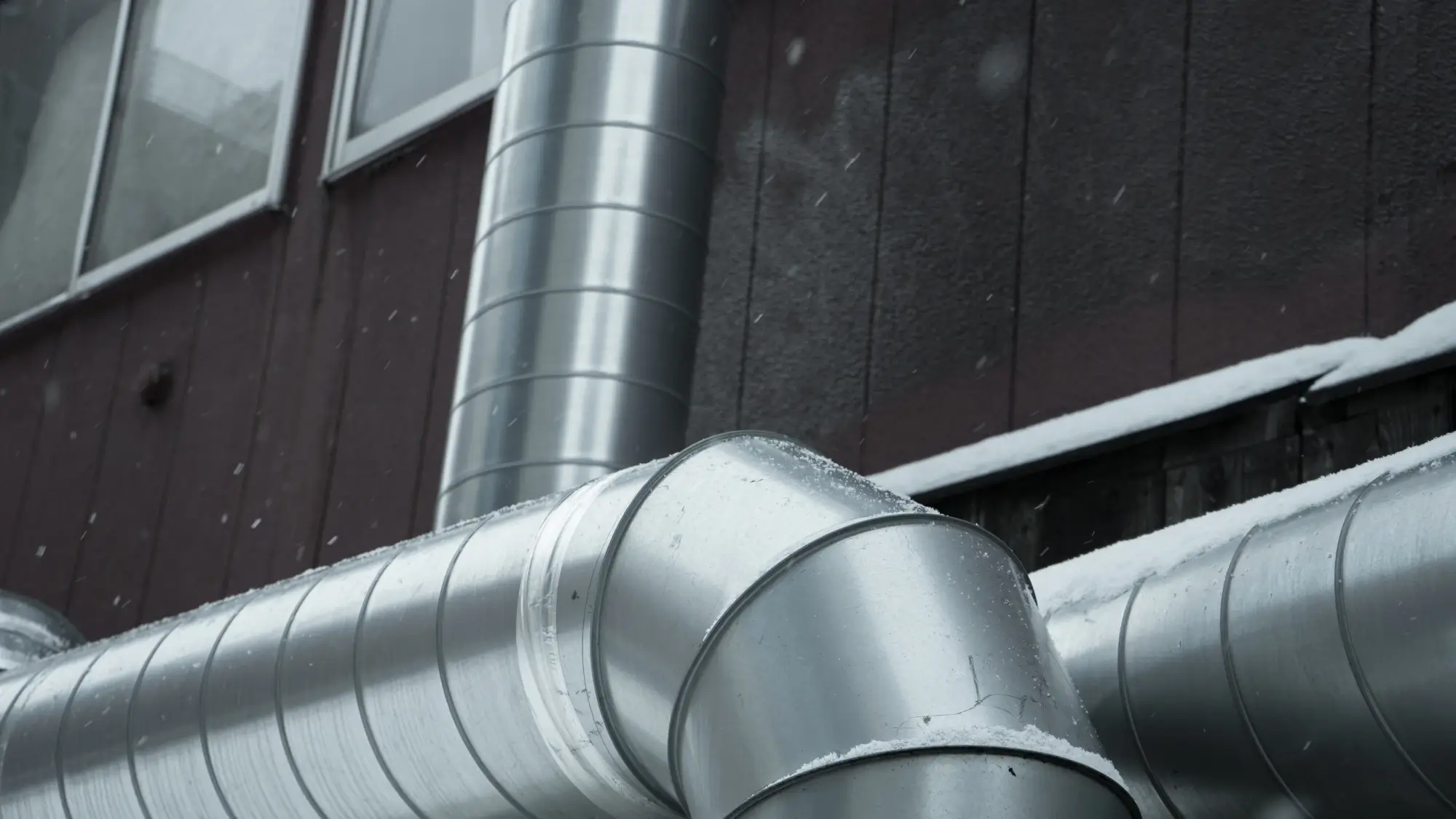 Galvanized spiral ductwork installation showing complex joints that increase total installed cost compared to modular clamp-together systems.