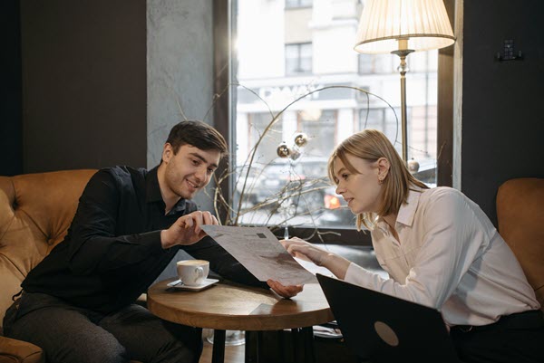 Professionals collaborating on a document in a coffee shop setting.