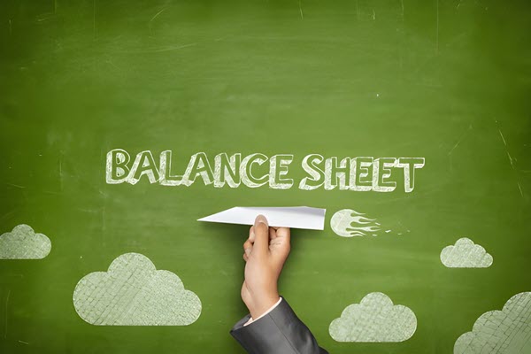 Green chalkboard background with "BALANCE SHEET" text and a hand launching a paper airplane, illustrating financial concepts.