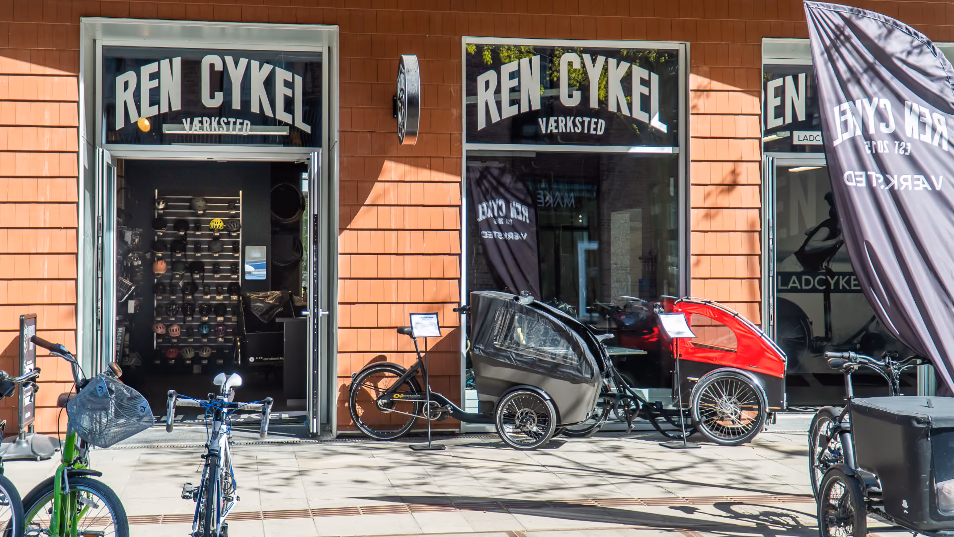 Udvalg af christiania el ladcykler og cykeltilbehør udenfor cykelværksted med fokus på cykelservice.