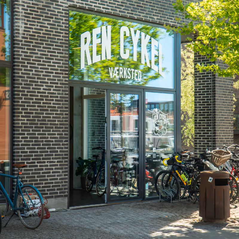 Ren Cykel værksted med cykler og ladcykler parkeret udenfor, fokus på cykelreparation og køb cykel.