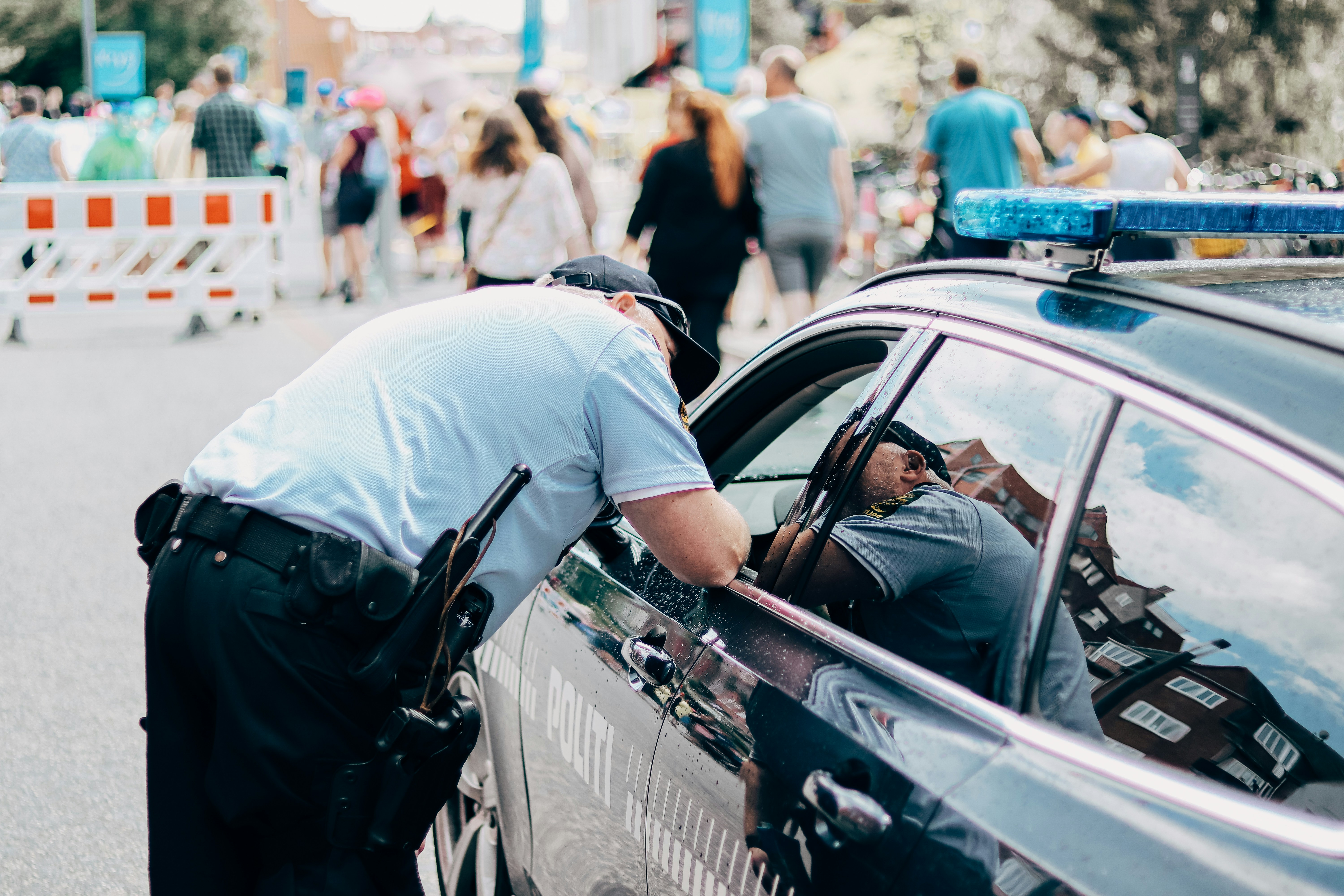 Betjente fra politiet i samtale ved en patruljebil under en offentlig begivenhed – relevant i forhold til spørgsmålet: Må man køre fuld på cykel, og hvordan politiet håndhæver reglerne