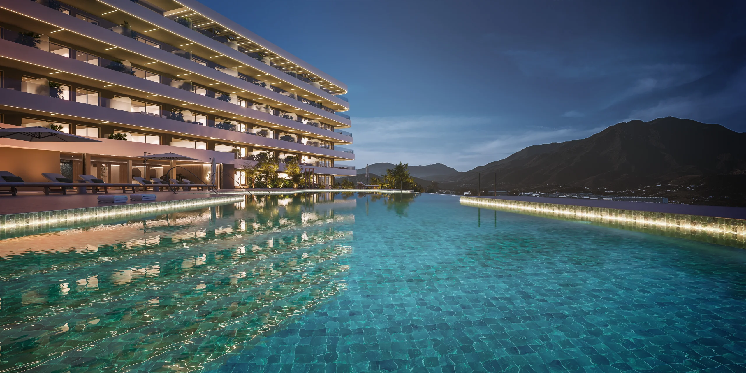 Rendering at dusk of a large illuminated infinity pool with teal tiles beside a lit apartment building, mountains silhouetted behind – Maralto, a 3-bedroom apartment in Las Mesas, Estepona