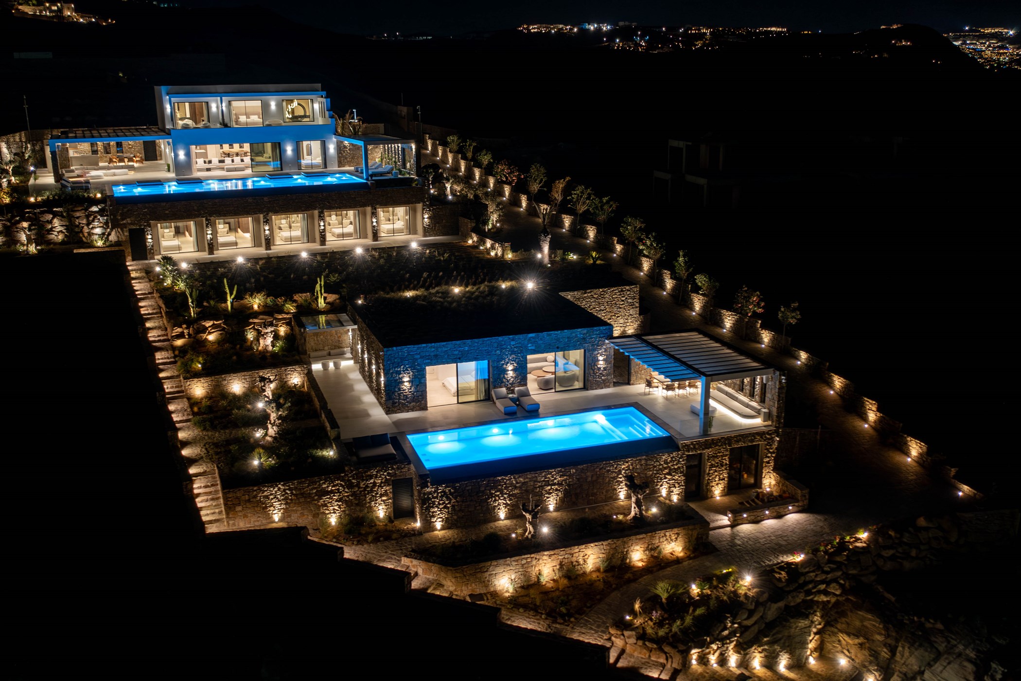 Night aerial view of a large stone-built villa complex with two illuminated pools, a pergola-covered dining terrace and stepped stone terraces – Diaz Grande, a 13-bedroom villa