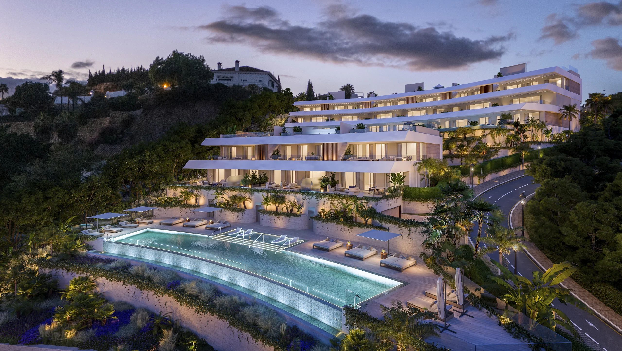 Rendering of a terraced white apartment building on a hillside at dusk, illuminated above a tiered communal infinity pool lined with sun loungers – Solenne, a 3-bedroom apartment in Benahavís, Málaga, Costa del Sol