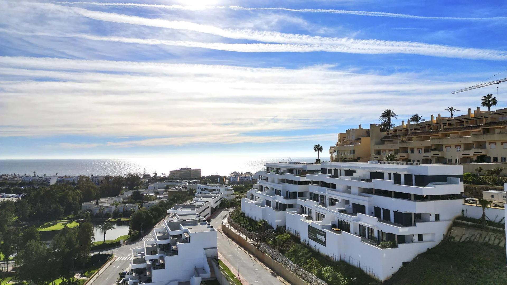 Aerial view of white hillside apartment buildings overlooking the sea and coastal town in the distance – Navigolf Suites, a 3-bedroom apartment in La Cala de Mijas, Mijas, Málaga