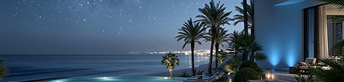 Palm trees silhouetted against a starlit sky over the ocean, with a villa terrace and city lights across the bay – USA