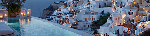 Infinity pool overlooking a whitewashed Cycladic village on a cliffside at dusk – Greece