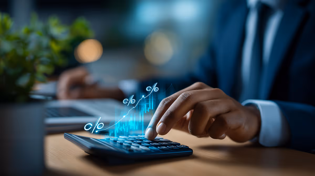 Person in suit using a calculator with glowing percentage signs and rising graph overlay.