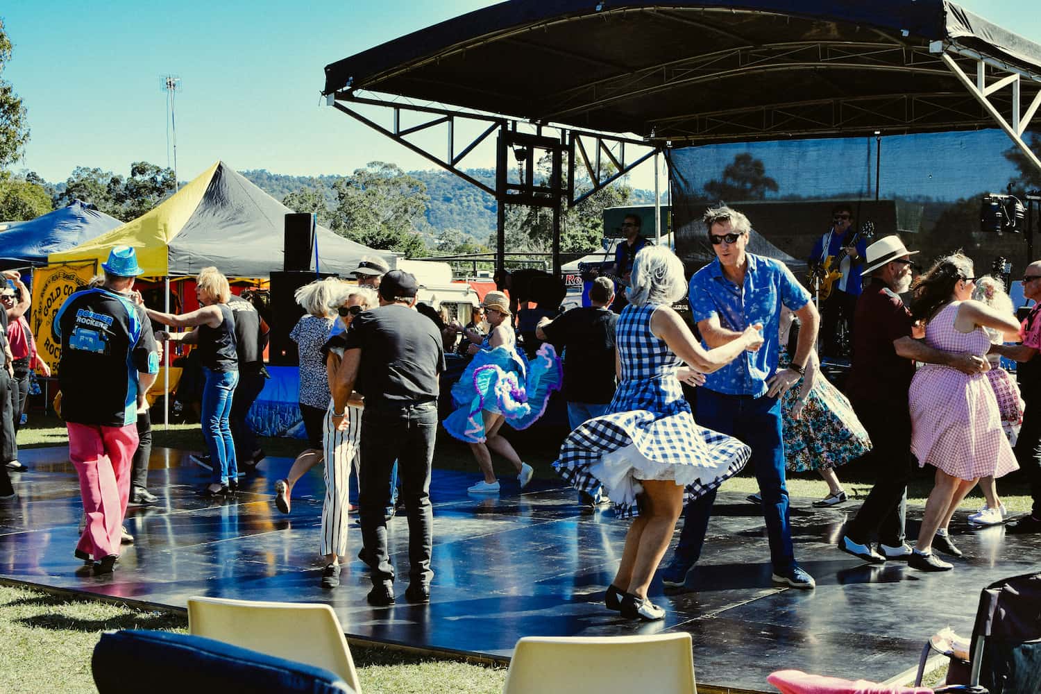 People dance to live music on an outdoor stage at a festival.