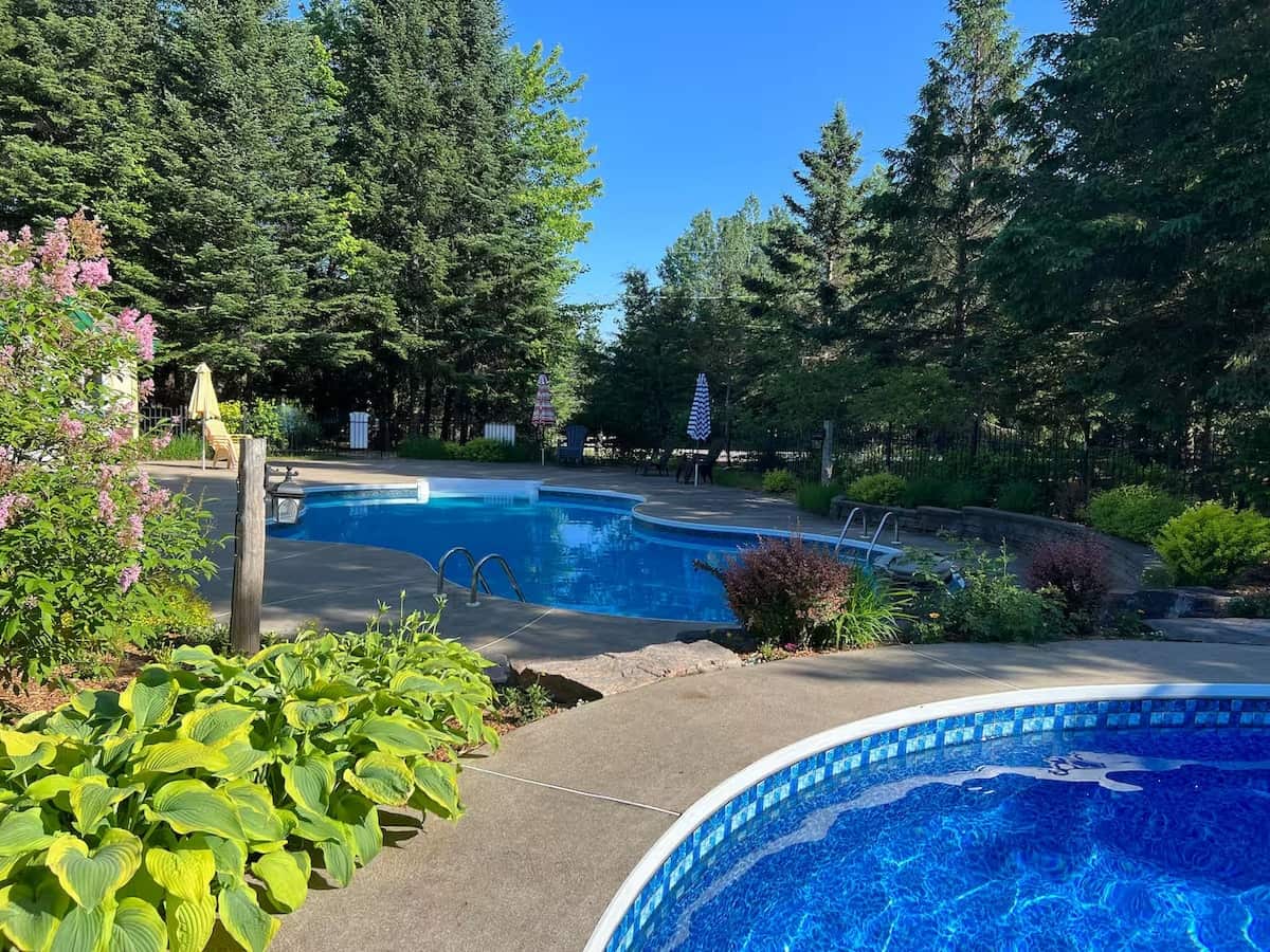 Large outdoor swimming pool surrounded by trees from HM Vacations Rentals.