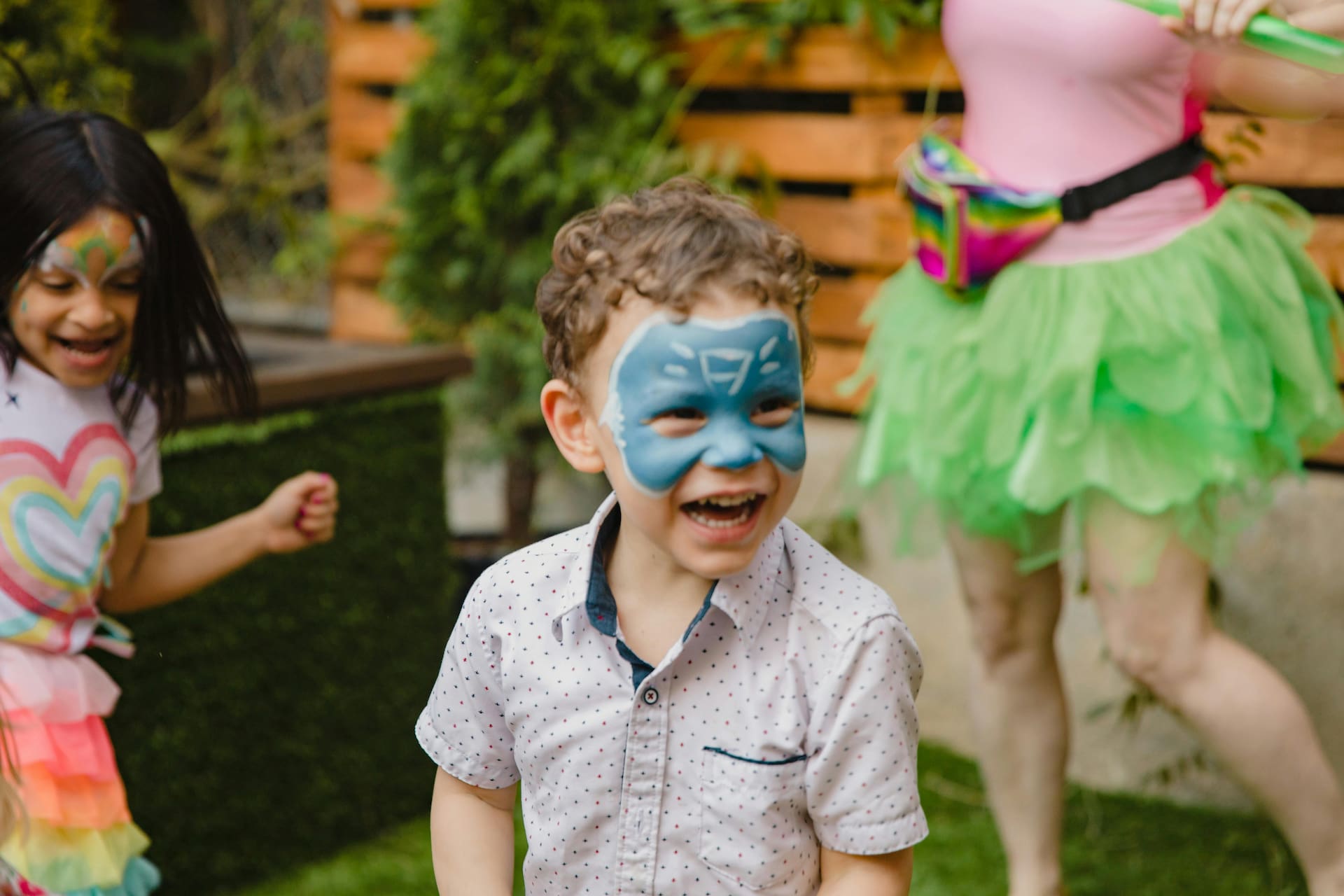 Un enfant souriant avec du maquillage bleu sourit à l'extérieur avec d'autres enfants à Mont-Tremblant