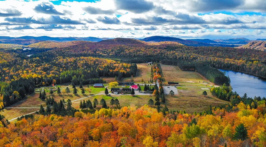 Vue aérienne du Domaine Saint-Bernard à Mont Tremblant, entouré d'arbres d'automne et d'un lac.