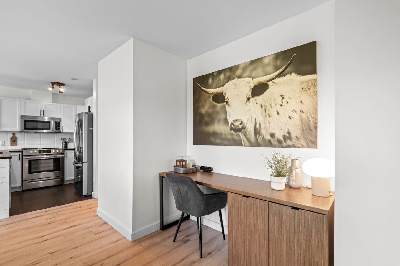A modern home office setup with a desk, chair, and large artwork, suitable for remote work.