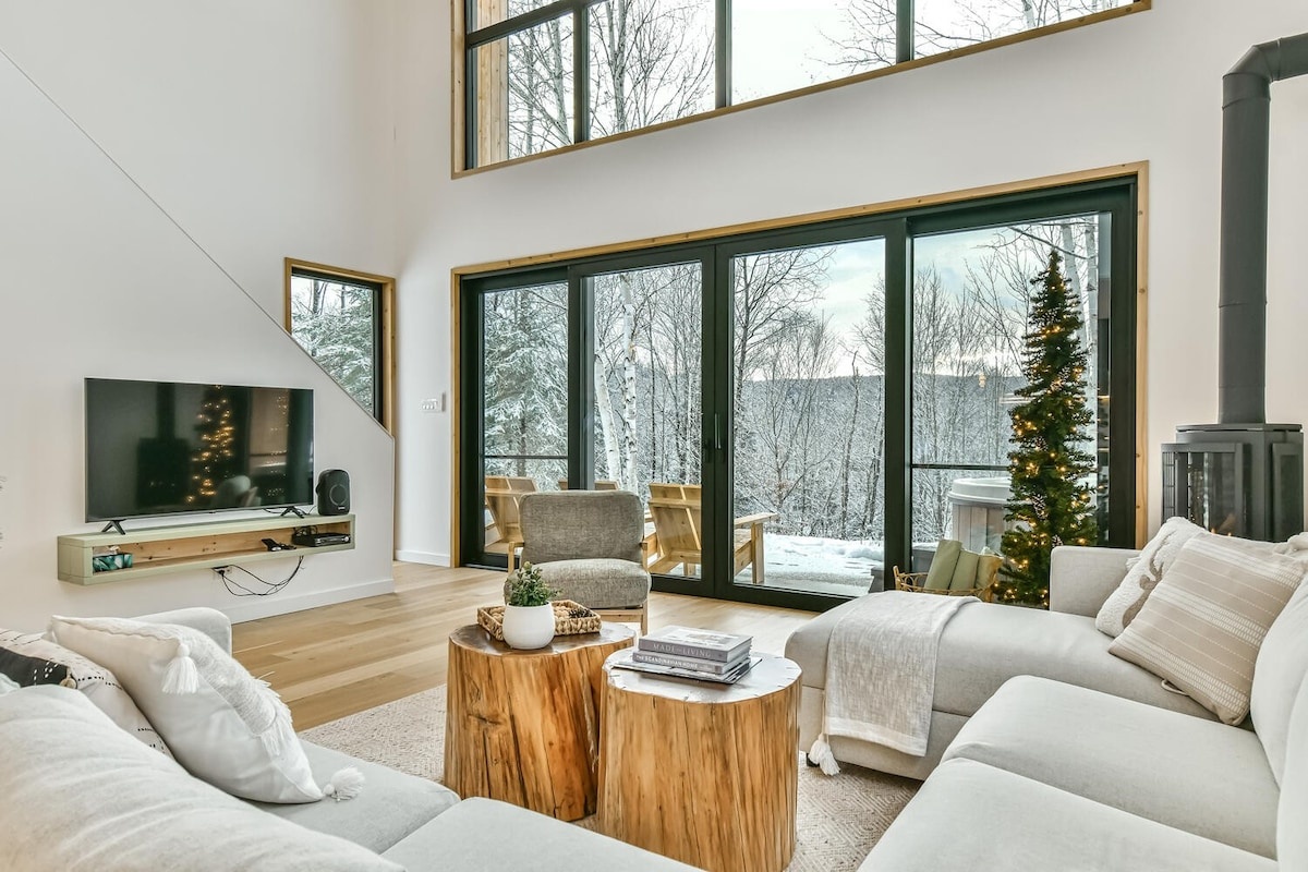 Cozy HM Vacation Rentals living room with a large sectional, TV, and forest views.