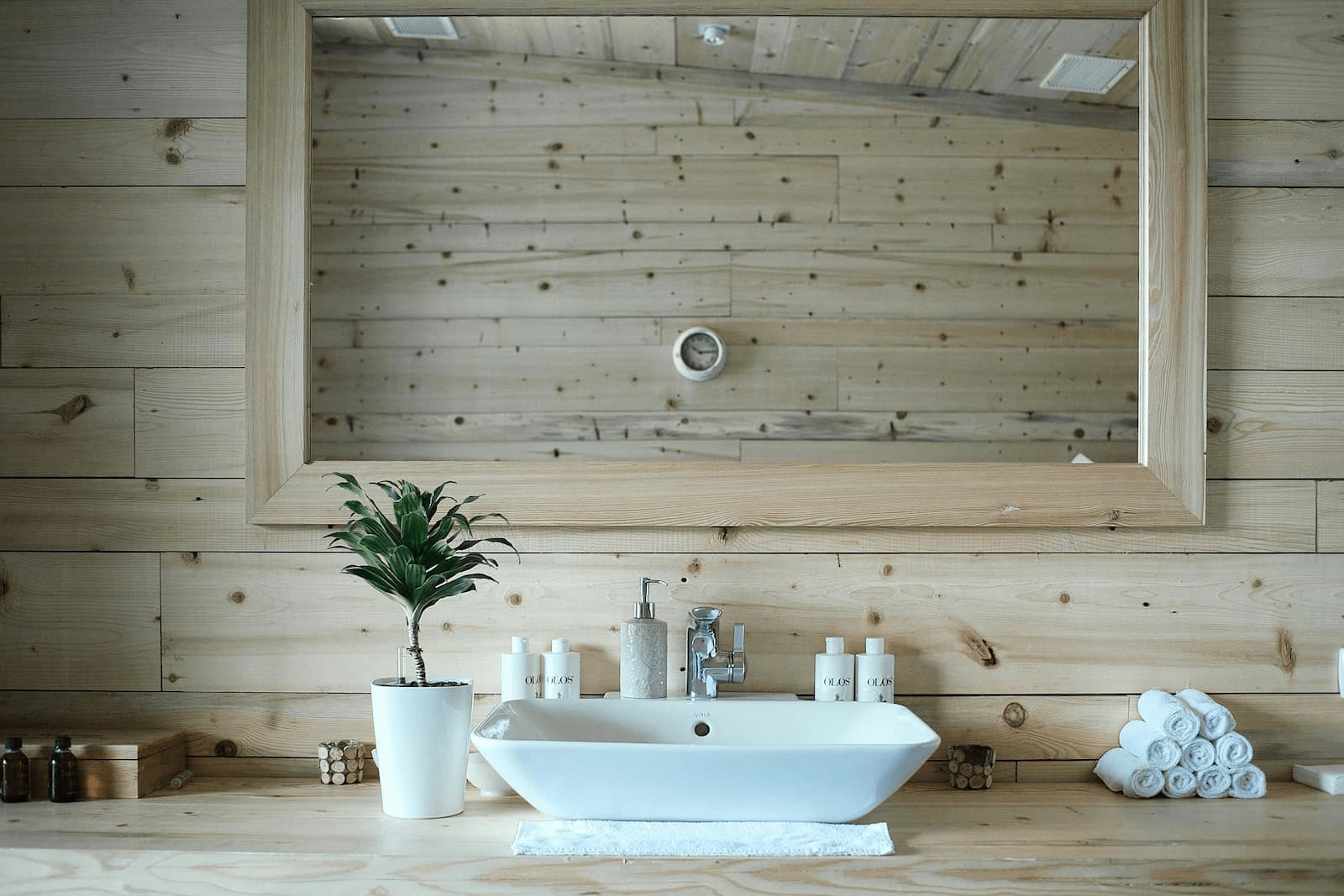 A bathroom featuring light wood paneling and a white sink, reflecting a focus on natural materials and sustainability.