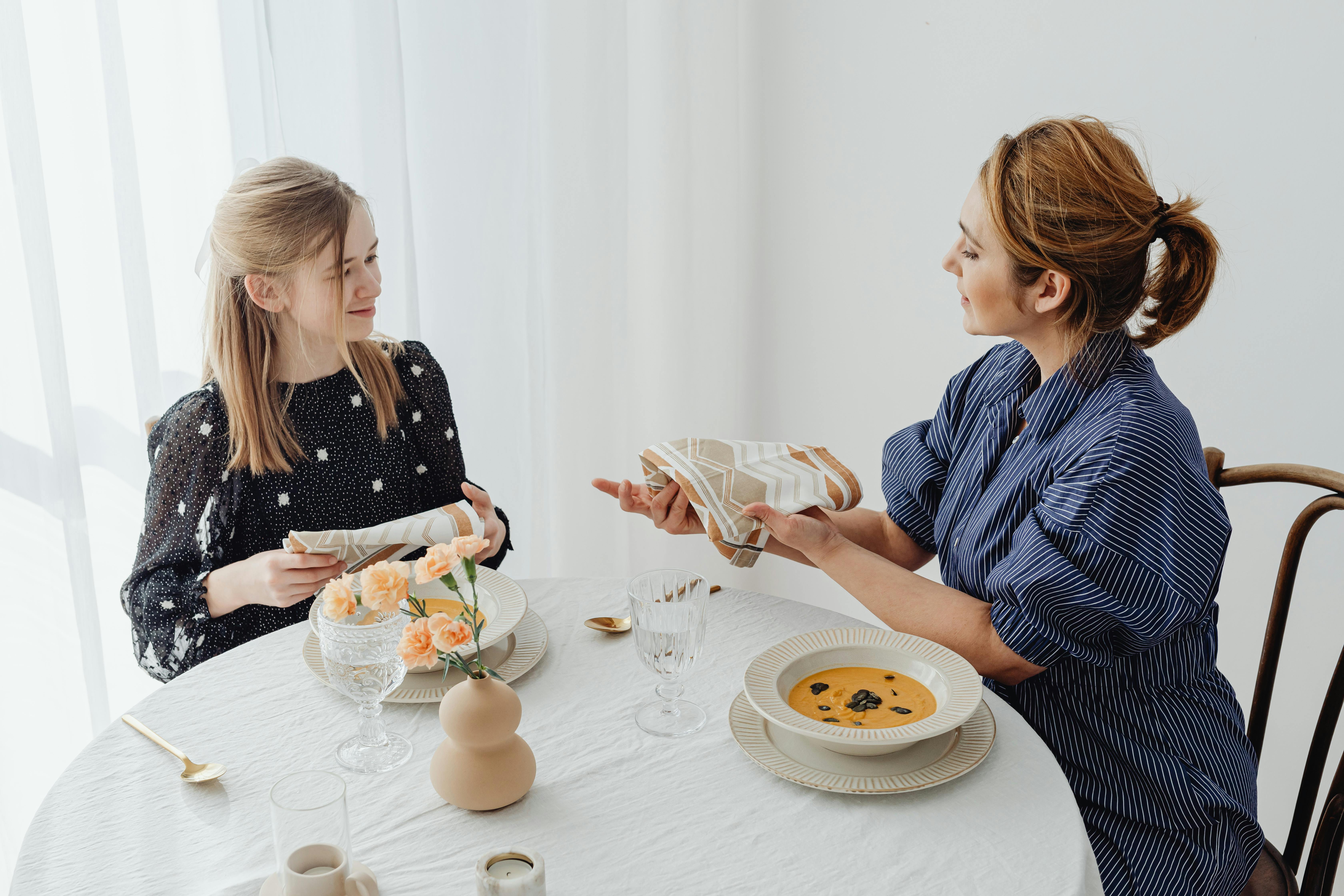 Deux femmes partagent un moment à table, prêtes à dîner.