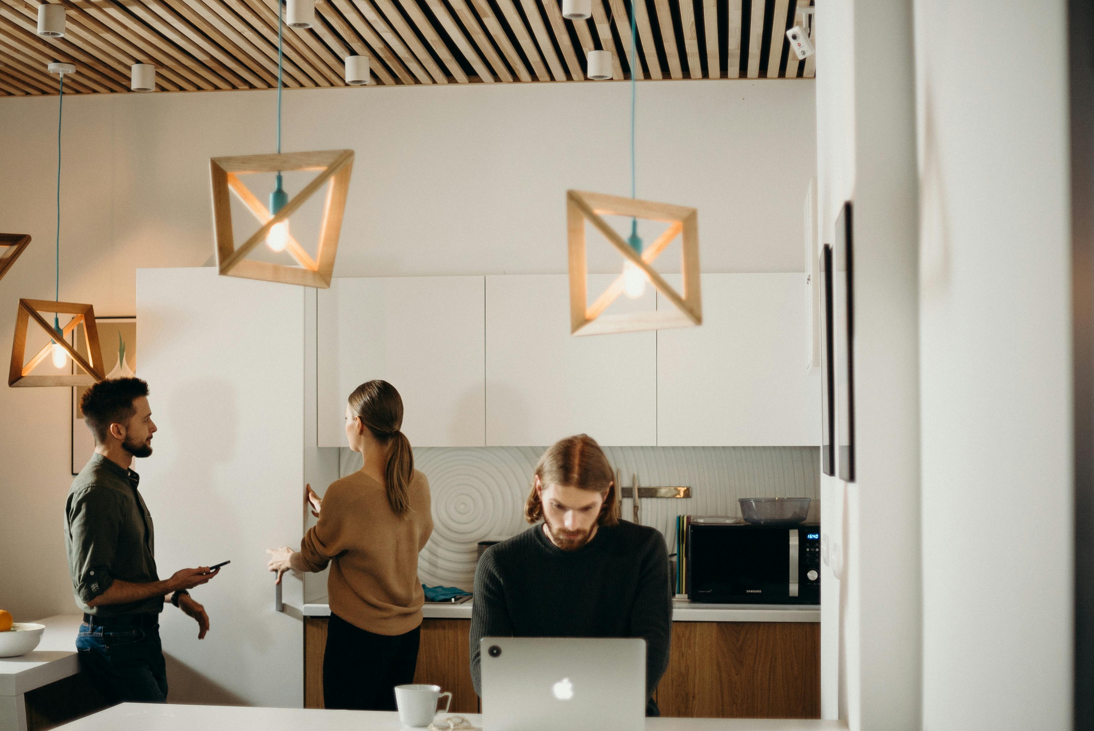 Collègues discutant et travaillant dans une cuisine de bureau moderne.