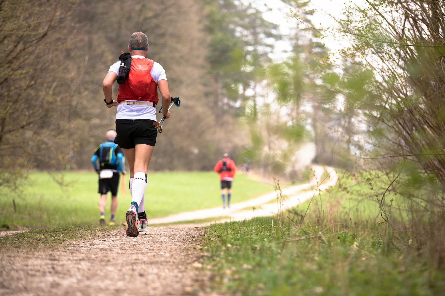 Athletes training for trail running on a forest path with gear and hydration packs