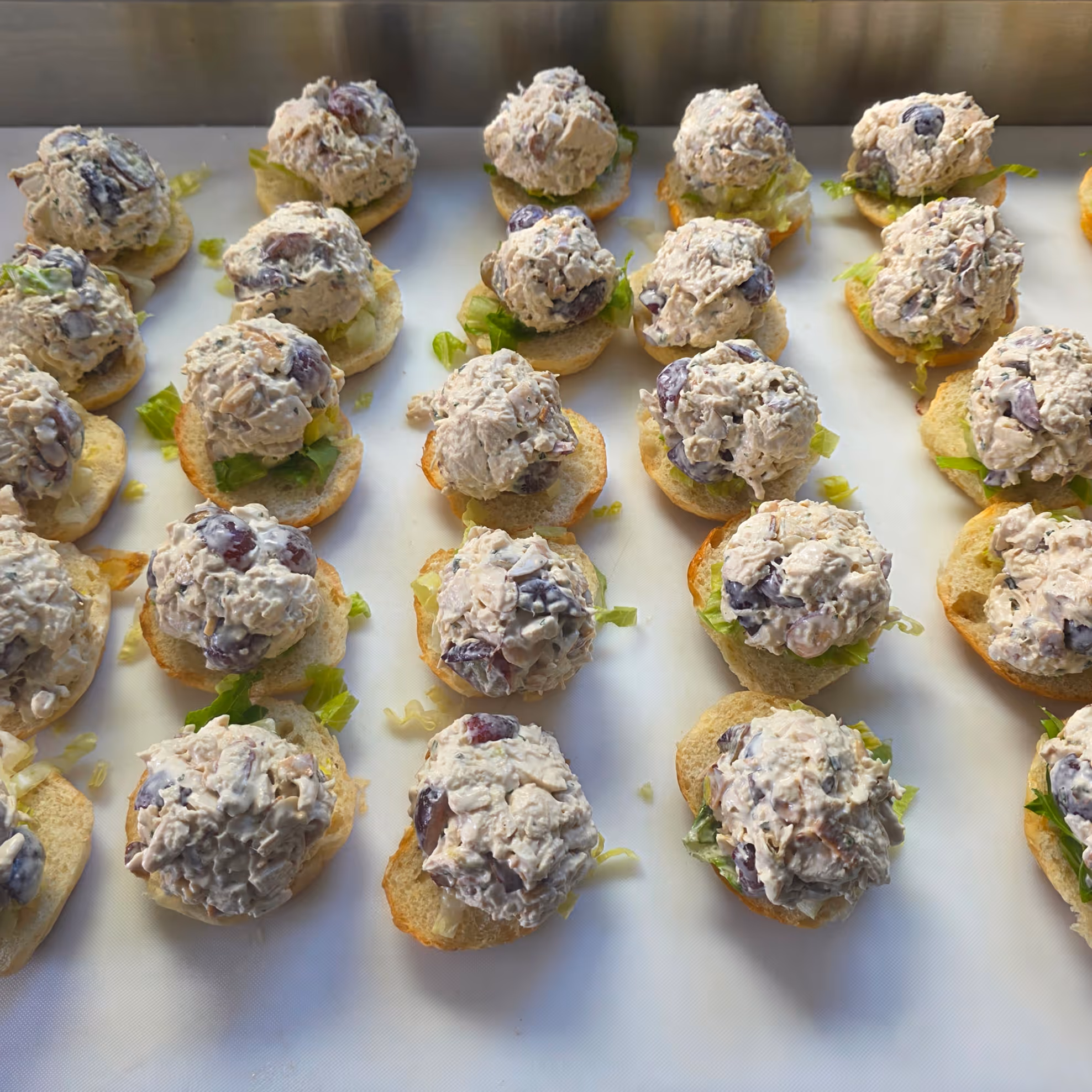 Preparing the tasty Grape Debate. A playful twist on a classic, this chicken salad has all white meat, red grapes, toasted almonds, and tarragon with arugula.