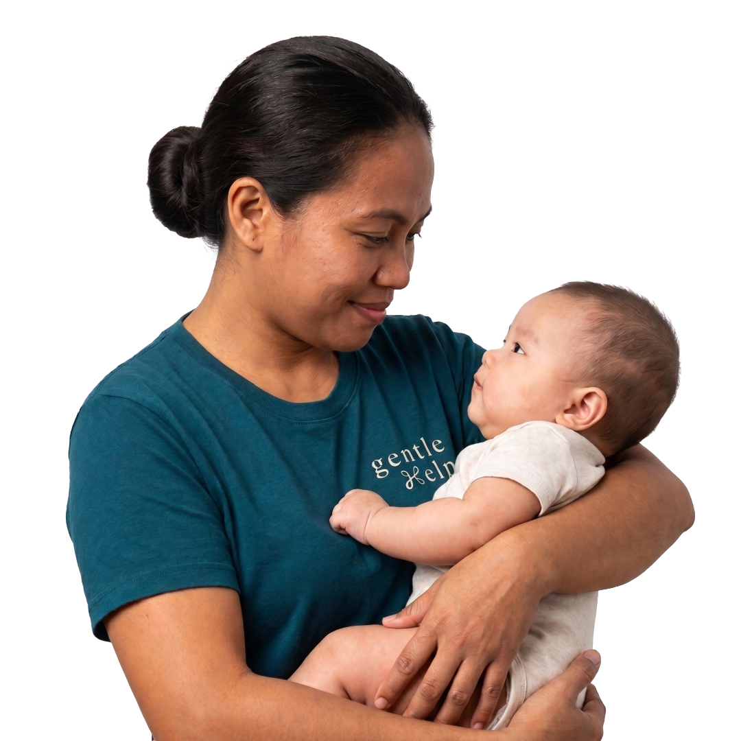 A smiling Filipino migrant domestic worker wearing a teal GentleHelp t-shirt lovingly cradles a baby .
