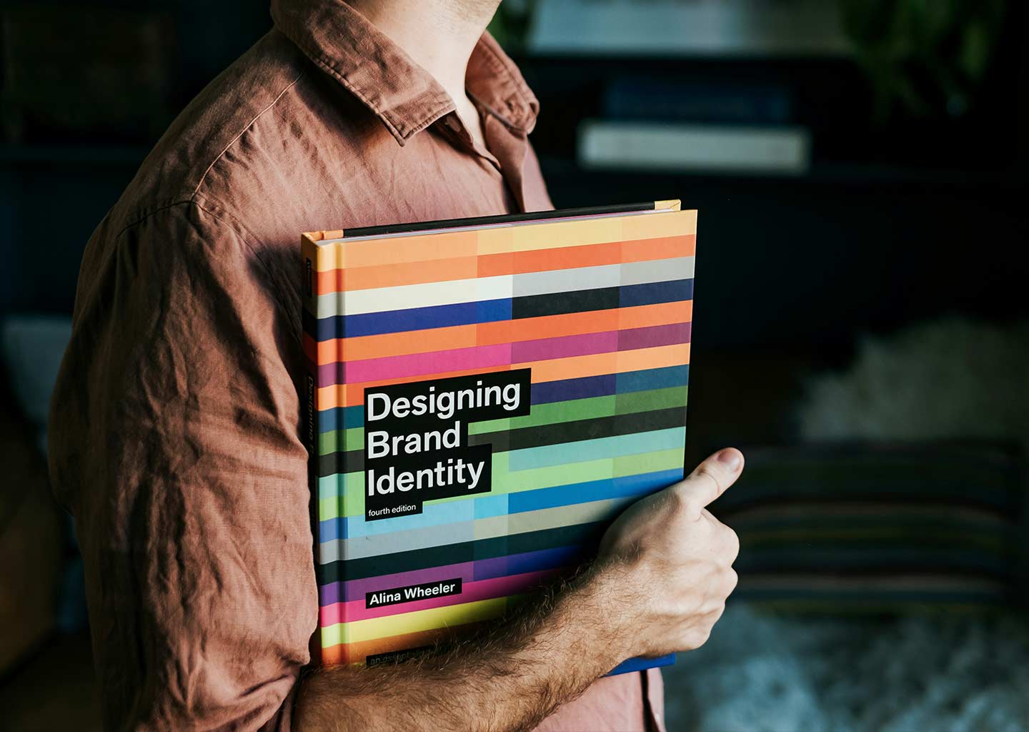 A man holds a book under his arm by Alina Wheeler titled Designing Brand Identity