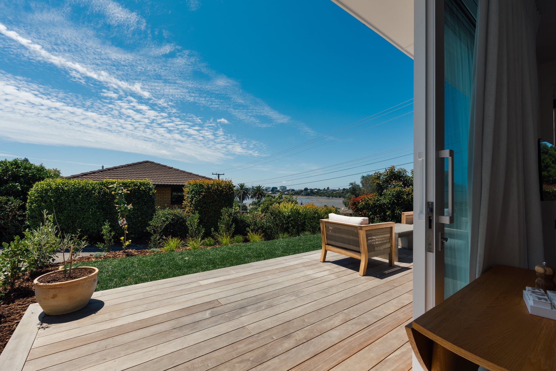 Spacious timber deck with potted plants and harbour views at Judea minor dwelling built by Gardo Group in Tauranga