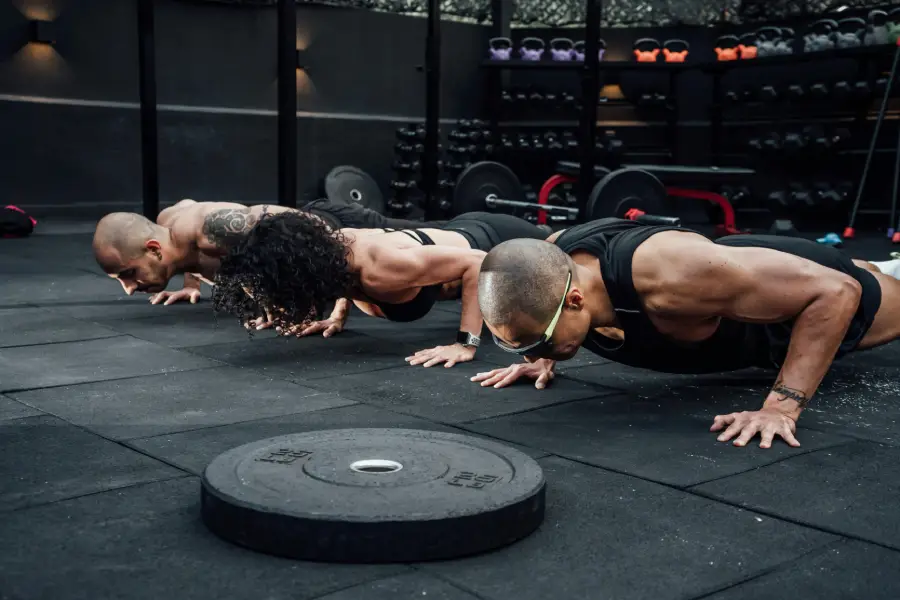 Group of athletes performing push-ups together in a gym, building upper body strength, core stability, and teamwork during group fitness training.