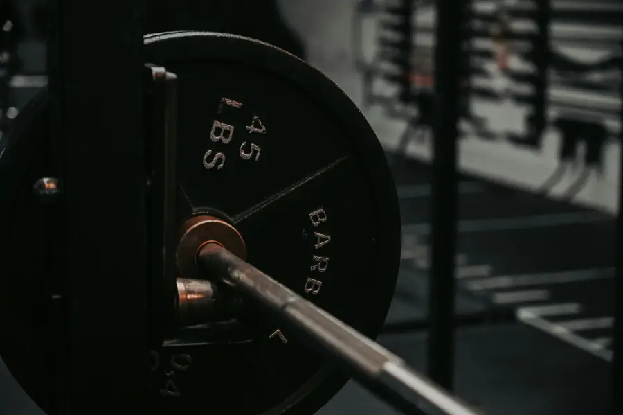 Close-up of a barbell loaded with 45-pound weight plates in a gym, highlighting strength training equipment used for elite performance workouts.