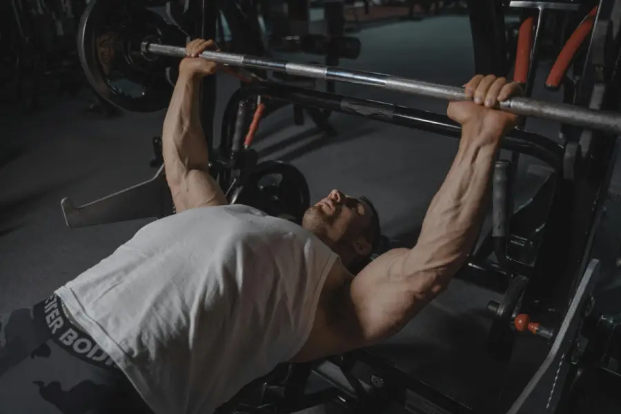 Athlete performing a barbell bench press at a gym, focusing on upper body strength development through structured strength training.