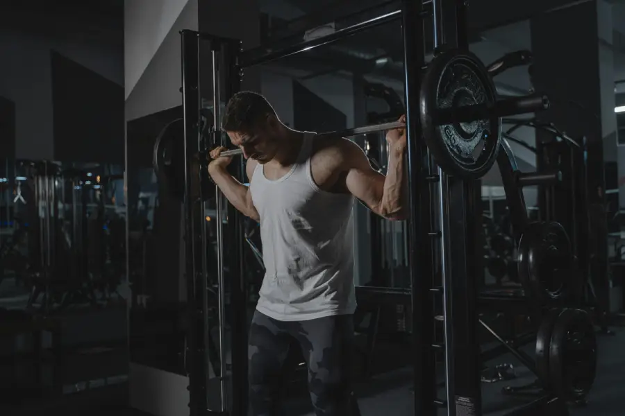 Athlete performing a barbell back squat inside a gym, focusing on lower body strength, stability, and full-body performance training.