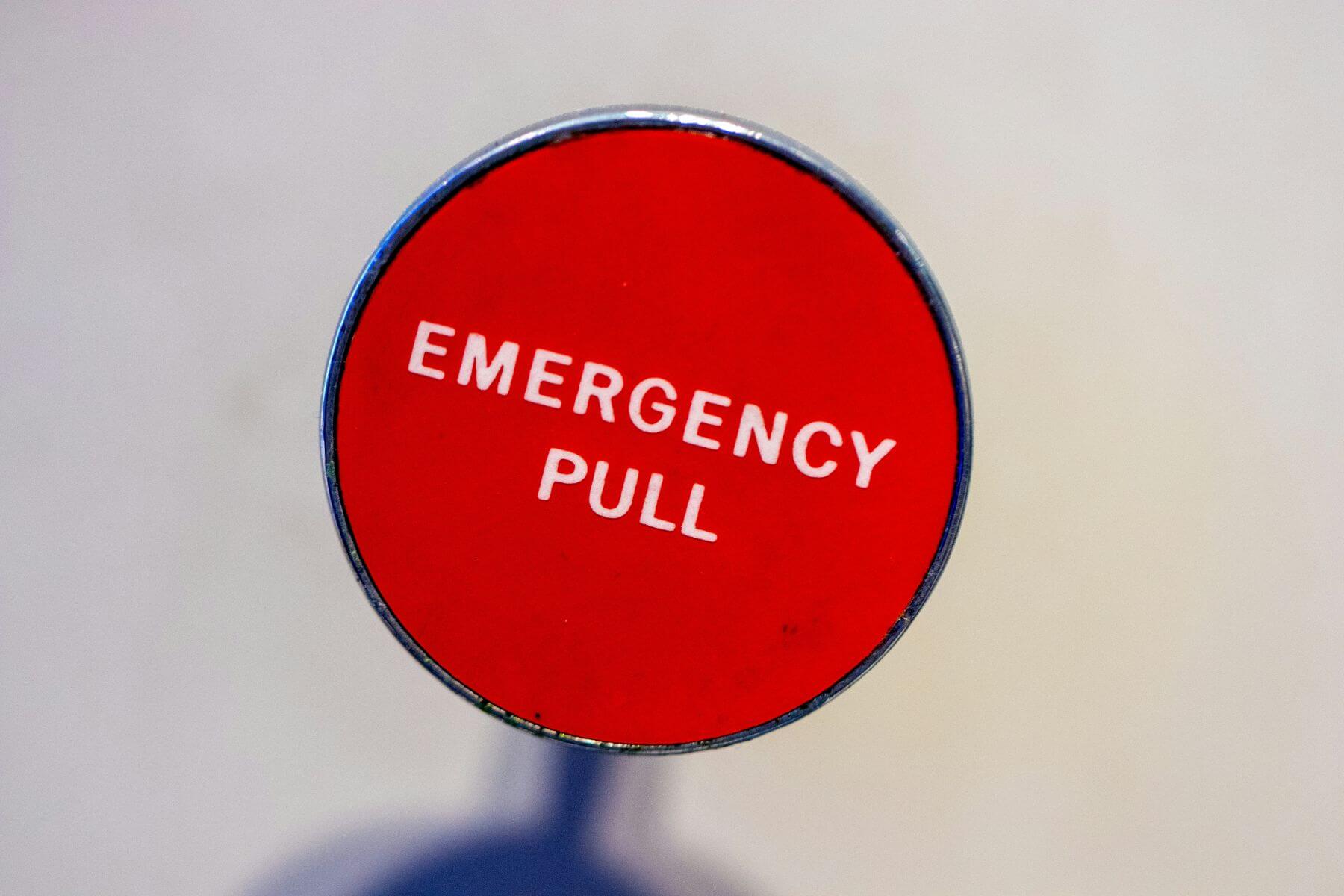 A bright red 'Emergency Pull' alarm switch representing the implementation of a business emergency notification system.
