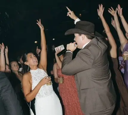 Wedding couple dancing at the reception with the groom holding a microphone and singing.
