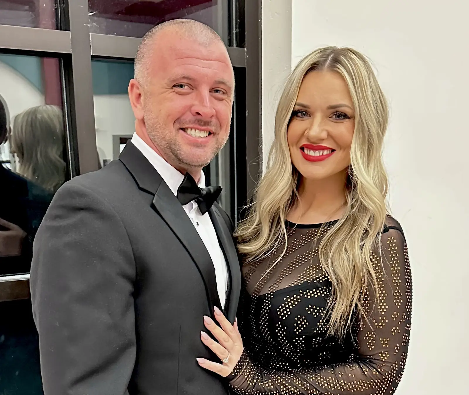 A couple posing for a photo taken by a guest at a dinner party