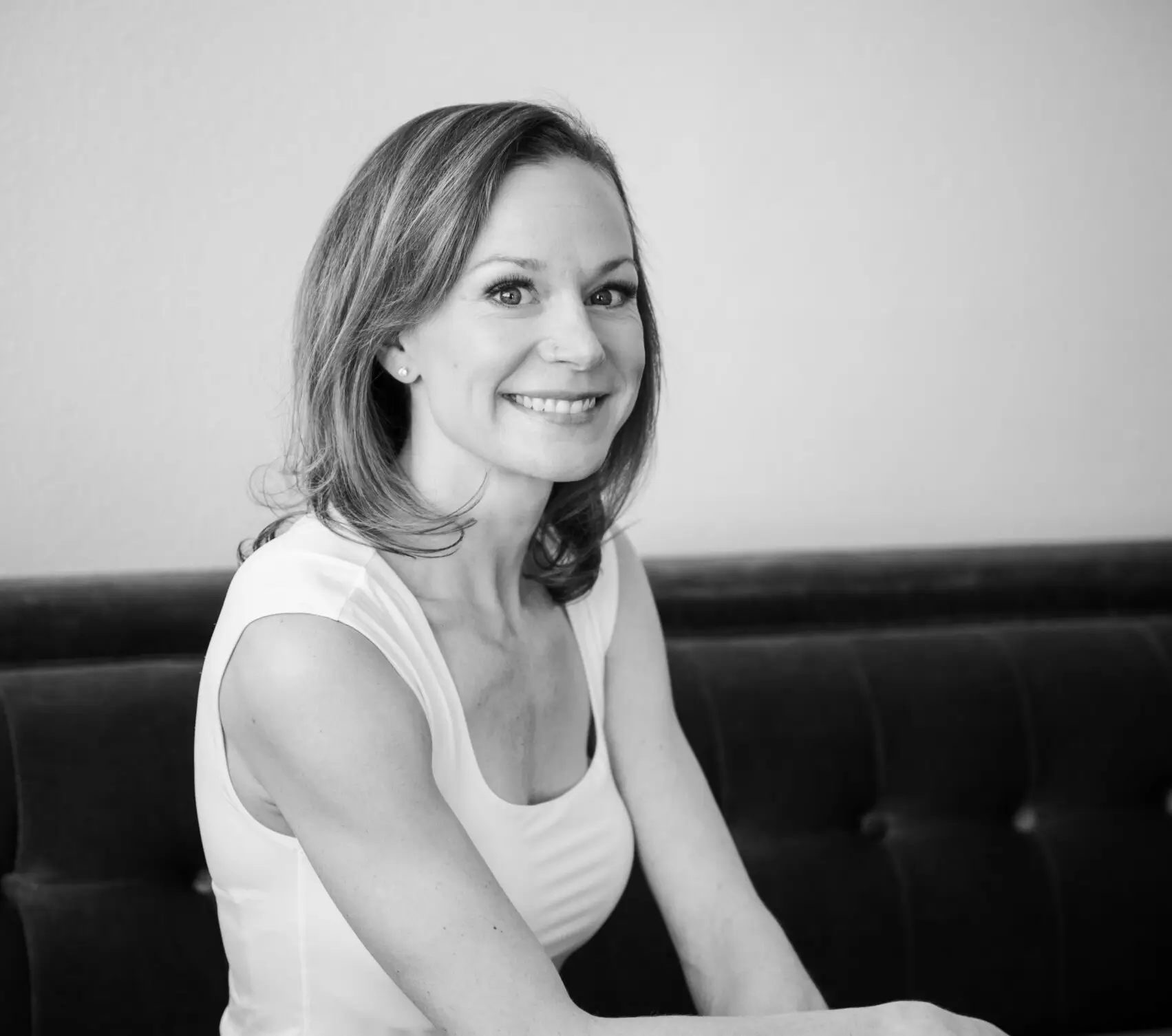 A photo of a lady sitting on a couch smiling