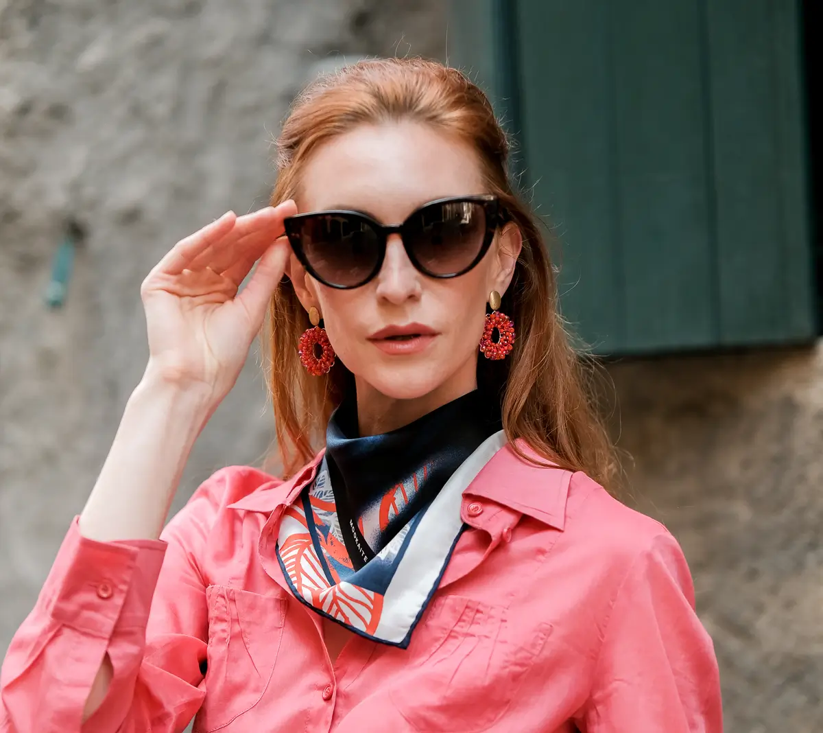 A woman wearing a pink jacket and sunglasses
