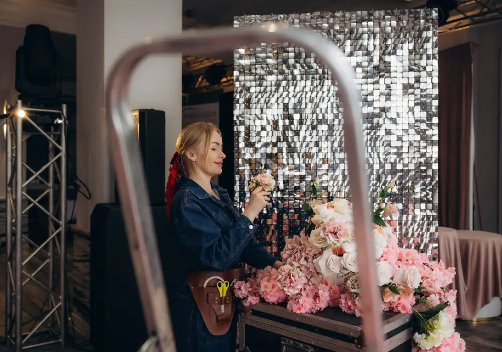 Florist decorating a sequin shimmer wall with pink roses and hydrangeas for a wedding