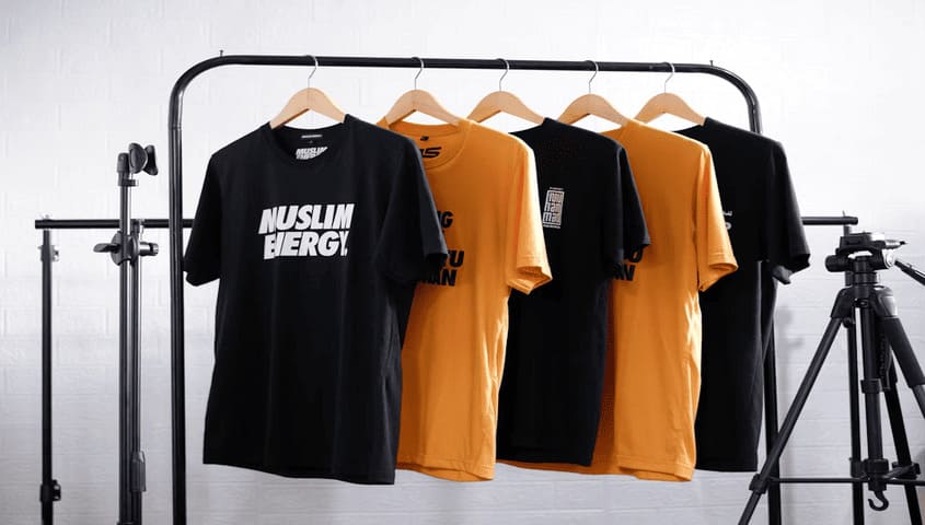 Black and orange DTG printed T-shirts hanging on a rack