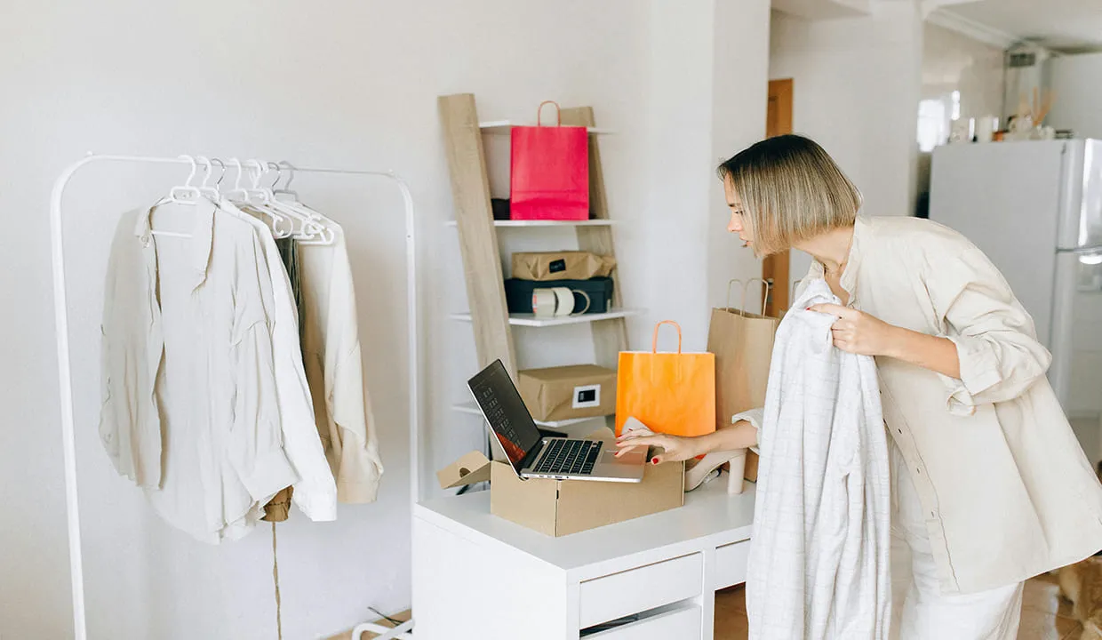 Woman selling custom clothing online and packing orders for shipping