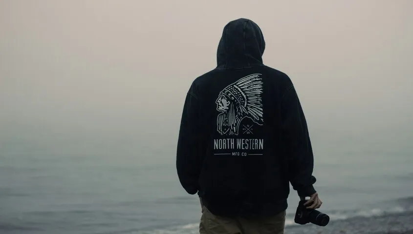 boy wearing a black hoodie has a custom-designed print on his back.