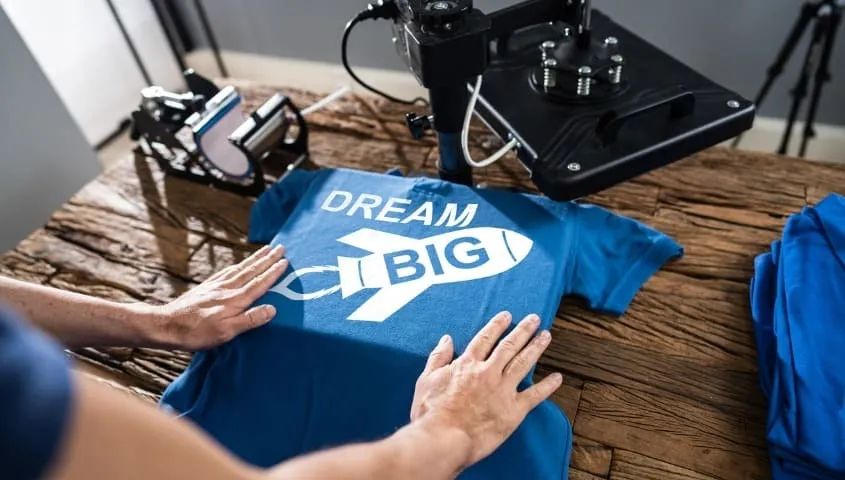 A man showing a print on demand shirt and the printer