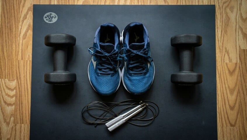  Weightlifting dumbbells and sports shoes are placed on the yoga mat.
