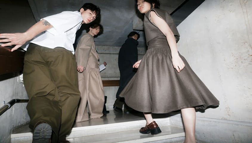 A group of people are wearing minimalist Gen Z-style clothes in the stairwell.