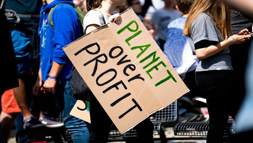 Gen Z fashion statement style, person raising a “Planet Over Profit” sign