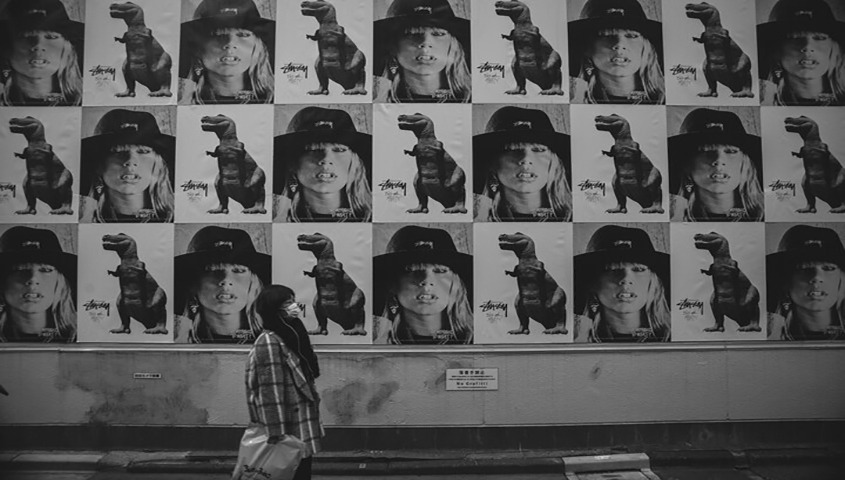 A woman standing before a black-and-white photo wall, reflecting artistic clothing brand identity