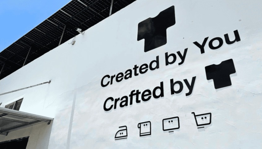 Tapstitch brand logo on a professional facility used for how to make 100 dollars a day through custom apparel scaling.