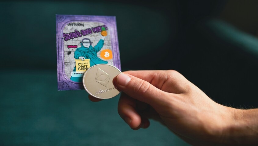 Holding an Ethereum coin and NFT card, a digital asset strategy for how to make 100 dollars a day.
