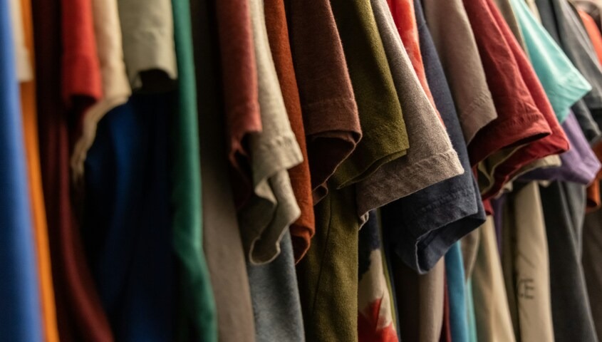 Fashion-forward t-shirts hanging on a rack for a professional print-on-demand t-shirt brand.